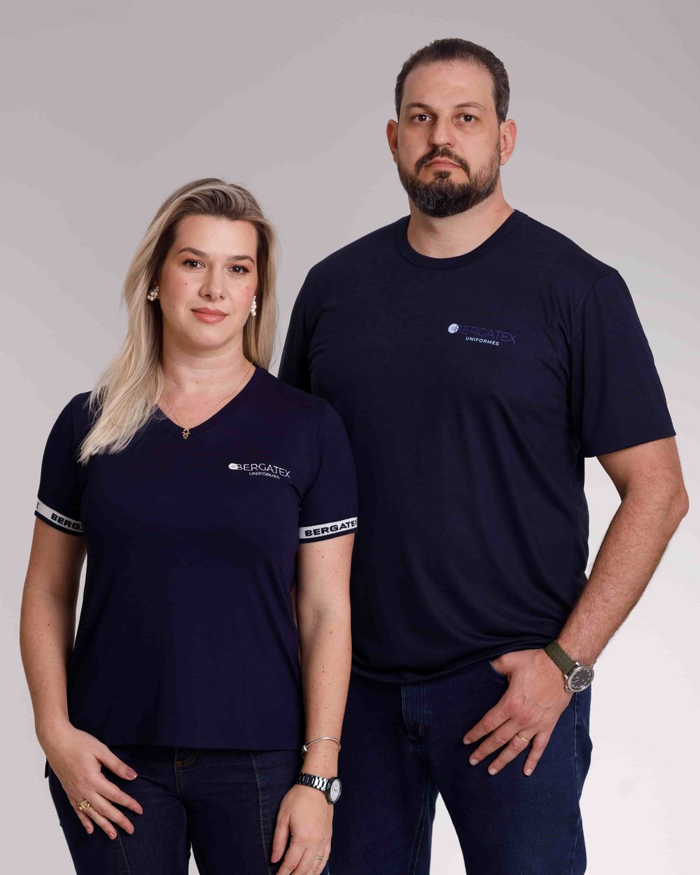 Homem e mulher vestindo camisa polo marinho da Bergatex com punho personalizado